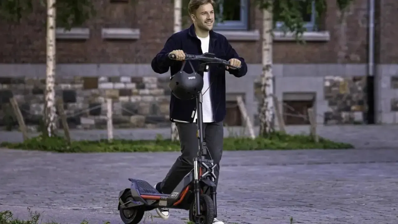 Un homme souriant sur une trottinette électrique puissante, dépassant les 25 km/h. La réglementation sur ces engins est à considérer.
