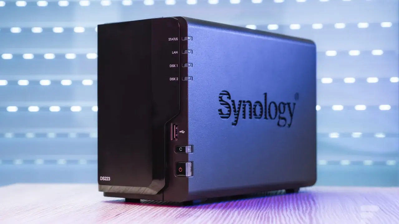 Un appareil Synology DS223, un nas stockage compact, est présenté sur un bureau en bois, avec un fond lumineux.