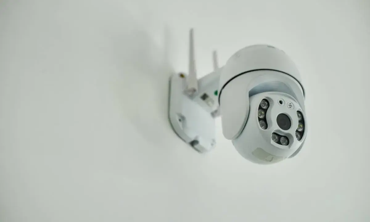Installation d'une caméra IP blanche sur un mur. Elle est orientable et dotée de plusieurs LED infrarouges.