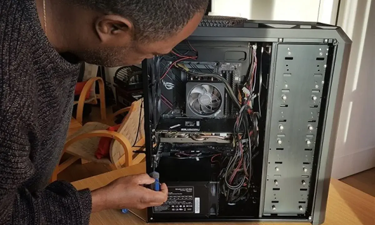 Un homme ajuste l'alimentation d'un PC. Il manipule un tournevis pour le sens alimentation pc.