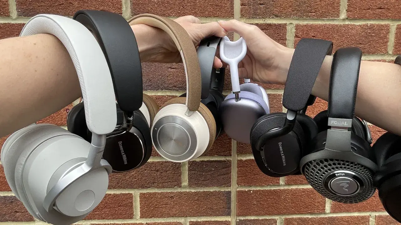 Collection de casques supra-auriculaires, certains tenus par des mains, sur fond de mur de briques.