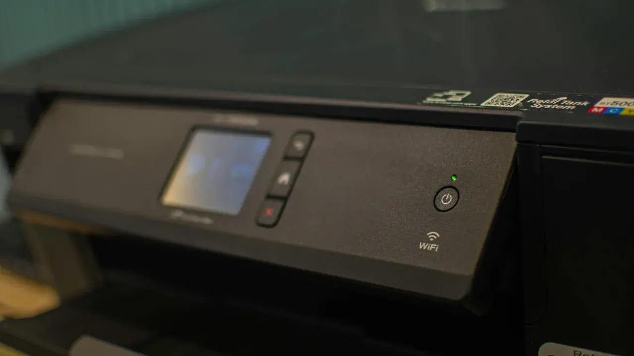 Panneau de contrôle d'une imprimante avec écran, boutons et indicateur Wi-Fi. Une caractéristique imprimante notable est sa connectivité sans fil.