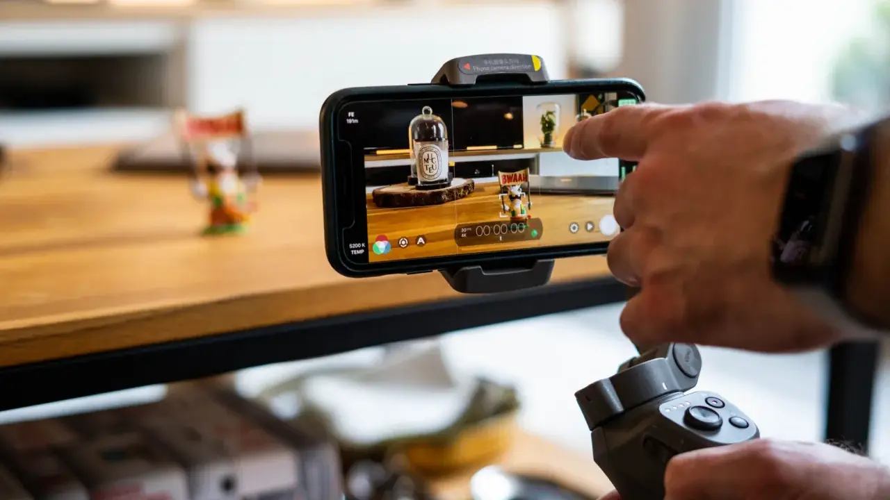 Main tenant, une main utilise un stabilisateur pour un enregistrement camera avec un smartphone.