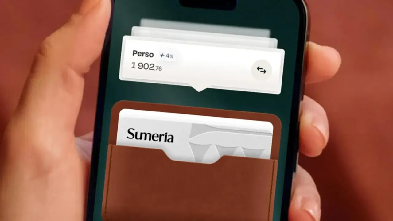 Une main tient un smartphone affichant l'application Sumeria. Une carte bancaire Sumeria est visible dans un étui en cuir marron.