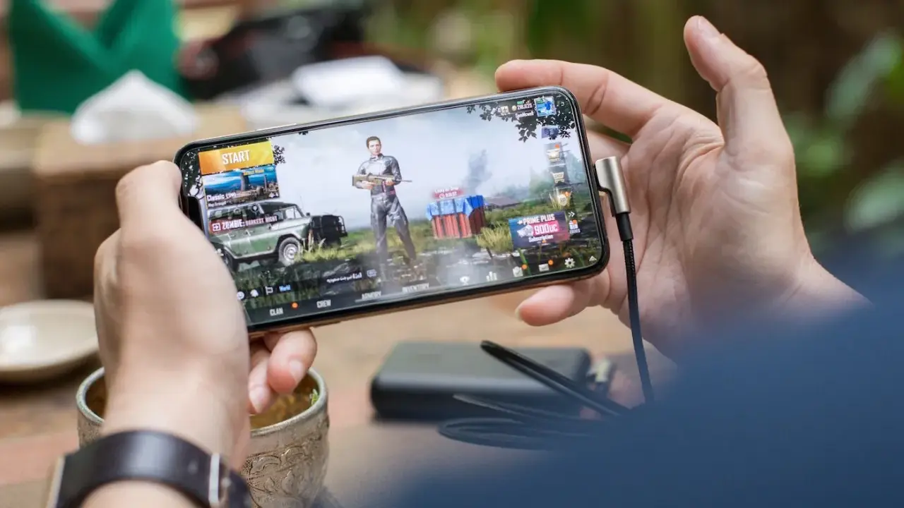 Main d'une personne tenant un smartphone affichant un jeu vidéo, parfait pour les jeux sans connexion.
