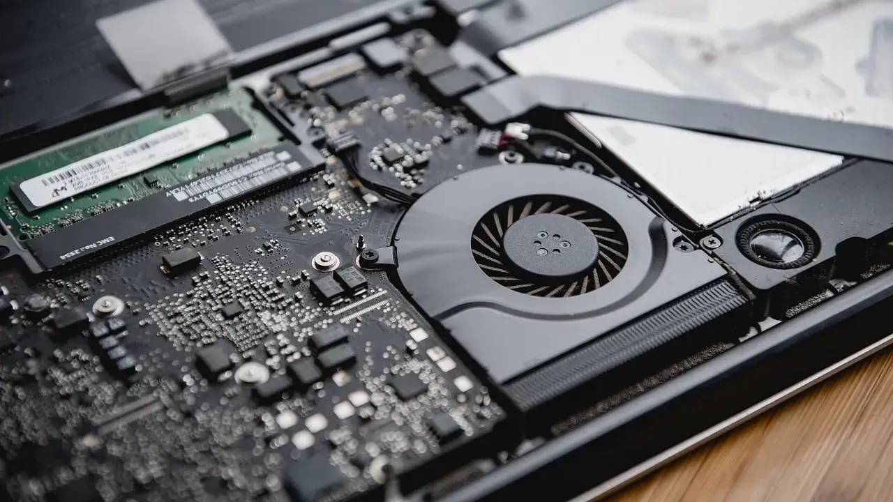 Intérieur d'un ordinateur portable ouvert, montrant la carte mère, le ventilateur et la RAM. La RAM est essentielle pour la définition de la performance.