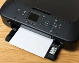 Imprimante noire avec une feuille de papier, prête à imprimer. Le câble USB est connecté, permettant la transmission des données.