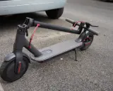 Trottinette électrique grise garée sur le trottoir. On se demande quelle sera sa durée de vie et son kilométrage avant de devoir la remplacer.