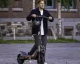 Un homme souriant sur une trottinette électrique puissante, dépassant les 25 km/h. La réglementation sur ces engins est à considérer.