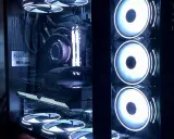 Intérieur d'un PC gamer avec éclairage RGB. On distingue la carte graphique, la carte mère, le système de refroidissement liquide et plusieurs ventilateurs. L'alimentation PC est bien visible.
