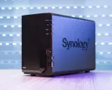 Un appareil Synology DS223, un nas stockage compact, est présenté sur un bureau en bois, avec un fond lumineux.