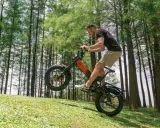 Un homme fait du vélo électrique en montée, le pneu avant décollé du sol. Il semble s'amuser, explorant quelle vitesse pour monter une côte en vélo électrique.