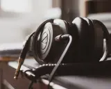 Gros plan sur un casque audio noir, avec son câble spiralé et sa prise jack dorée. La sensibilité du casque audio est palpable.