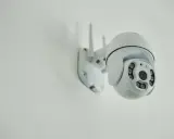 Installation d'une caméra IP blanche sur un mur. Elle est orientable et dotée de plusieurs LED infrarouges.
