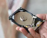Main d'une personne tenant un disque dur interne, montrant les plateaux réfléchissants et les composants électroniques. Il existe différents types de disques durs.
