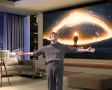 Un homme s'émerveille devant un vidéoprojecteur projetant une scène spatiale. Un guide pour comment choisir un vidéoprojecteur.