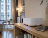 Routeur blanc moderne avec lumières bleues, offrant une connexion wifi ac stable pour un intérieur cosy. Un smartphone est posé à côté.