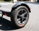 Roue de trottinette électrique sur la route. Le pneu semble dégonflé, rendant impossible de gonfler pneu trottinette.
