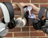 Collection de casques supra-auriculaires, certains tenus par des mains, sur fond de mur de briques.