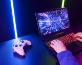 Un joueur utilise un PC portable gamer avec un clavier rétroéclairé. Une manette est posée à côté. Comment choisir son PC portable gamer ?