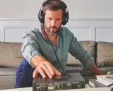 Homme avec casque audio, ajustant un appareil audio. L'impédance du casque audio est cruciale pour une écoute optimale.