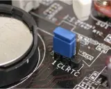 Gros plan sur une carte mère, montrant la pile bouton et le cavalier CLRTC pour réinitialiser le CMOS.