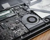 Intérieur d'un ordinateur portable ouvert, montrant la carte mère, le ventilateur et la RAM. La RAM est essentielle pour la définition de la performance.
