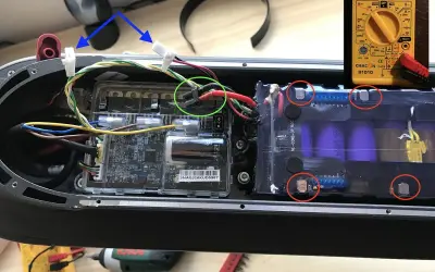 Le fusible de la trottinette électrique est ici, près des connexions de la batterie. Un multimètre est visible.