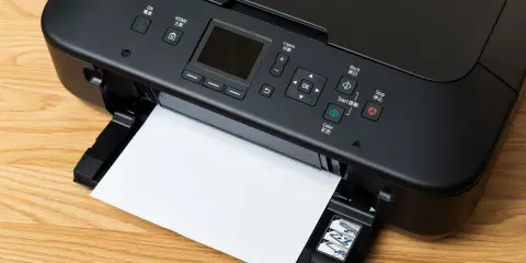 Imprimante noire avec une feuille de papier, prête à imprimer. Le câble USB est connecté, permettant la transmission des données.