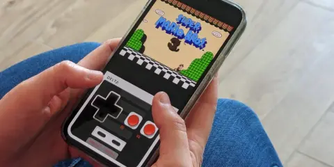 Jouer à Super Mario Bros sur iPhone avec l'émulateur Delta. La manette virtuelle rappelle les consoles d'antan.