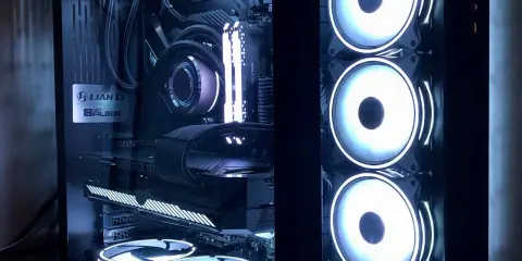Intérieur d'un PC gamer avec éclairage RGB. On distingue la carte graphique, la carte mère, le système de refroidissement liquide et plusieurs ventilateurs. L'alimentation PC est bien visible.