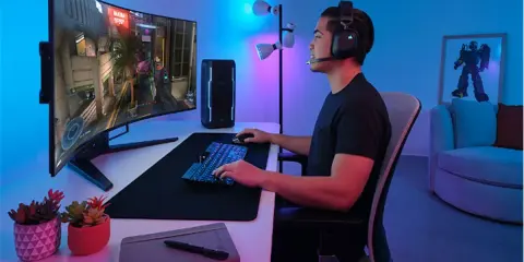 Un joueur concentré sur un écran d'ordinateur incurvé, profitant d'une immersion totale dans son jeu. La taille de l'écran offre une expérience visuelle captivante.