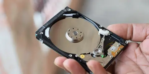 Main d'une personne tenant un disque dur interne, montrant les plateaux réfléchissants et les composants électroniques. Il existe différents types de disques durs.