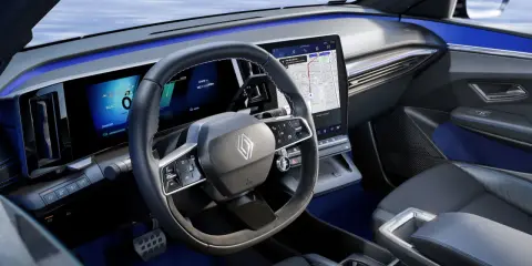 Tableau de bord moderne de la future Renault Mégane, avec écrans numériques, volant multifonction et éclairage d'ambiance bleu.