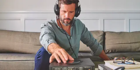 Homme avec casque audio, ajustant un appareil audio. L'impédance du casque audio est cruciale pour une écoute optimale.