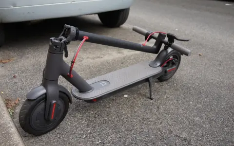 Trottinette électrique grise garée sur le trottoir. On se demande quelle sera sa durée de vie et son kilométrage avant de devoir la remplacer.