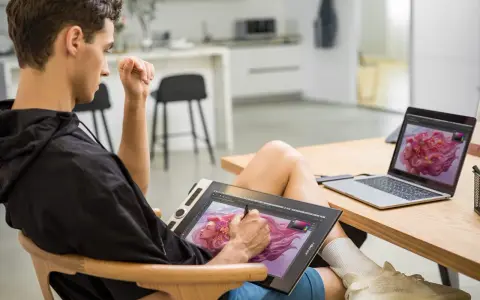 Un jeune homme utilise une tablette graphique pour créer une œuvre d'art numérique, sa configuration PC graphiste est prête pour l'inspiration.