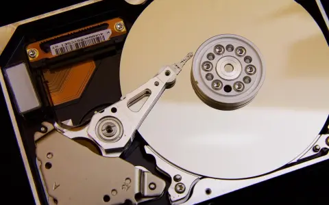 Vue rapprochée de l'intérieur d'un disque dur de PC, montrant le plateau, la tête de lecture/écriture et le moteur. L'emplacement du disque dur est essentiel pour le stockage des données.