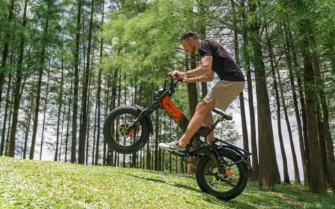 Un homme fait du vélo électrique en montée, le pneu avant décollé du sol. Il semble s'amuser, explorant quelle vitesse pour monter une côte en vélo électrique.