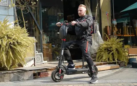 Un homme en tenue de moto est prêt pour un trajet de 10 km en trottinette électrique. Le temps est parfait pour explorer la ville.