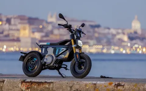 Une trottinette électrique BMW futuriste, aux lignes audacieuses, se dresse sur un quai, la ville illuminée en arrière-plan.