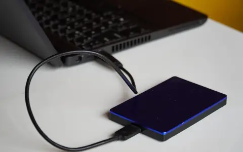 Un disque dur externe bleu est connecté à un ordinateur portable. Un guide pour comment choisir un disque dur.