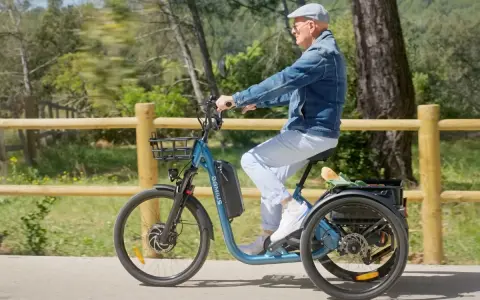 Un homme âgé roule sur un tricycle électrique bleu, son certificat d'homologation vélo électrique en poche.