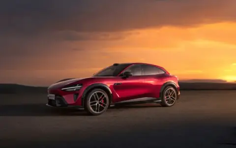 Le SUV rouge Xiaomi Yu7, aux lignes futuristes, se dresse sur un tarmac sous un ciel orangé spectaculaire.