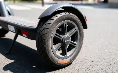 Roue de trottinette électrique sur la route. Le pneu semble dégonflé, rendant impossible de gonfler pneu trottinette.