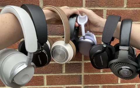 Collection de casques supra-auriculaires, certains tenus par des mains, sur fond de mur de briques.