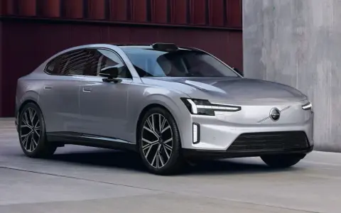 La nouvelle Volvo ES90, une berline électrique argentée aux lignes épurées, se gare devant un bâtiment moderne.