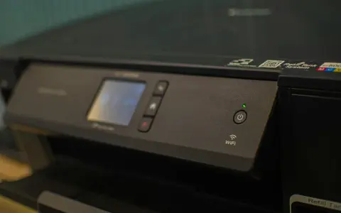Panneau de contrôle d'une imprimante avec écran, boutons et indicateur Wi-Fi. Une caractéristique imprimante notable est sa connectivité sans fil.