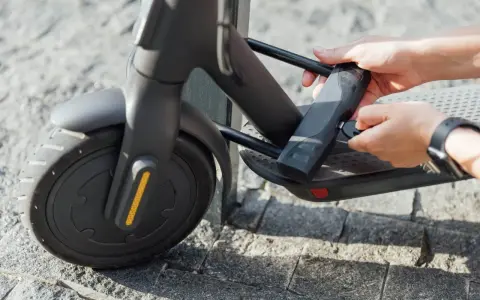 Mains tenant une clé pour comment attacher sa trottinette électrique. Le cadenas est fixé au cadre.