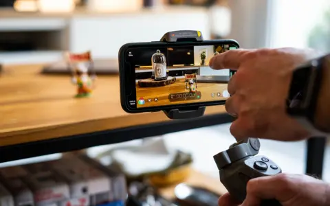 Main tenant, une main utilise un stabilisateur pour un enregistrement camera avec un smartphone.